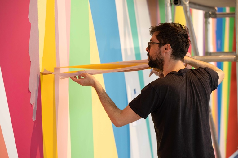 Alan Prazniak pulls masking tape from the wall during the installation of "Surrounding"