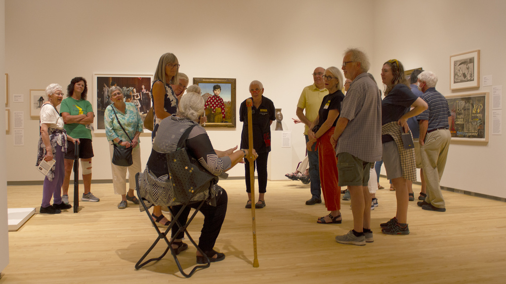 A tour group in an art museum gallery interacting with the docent