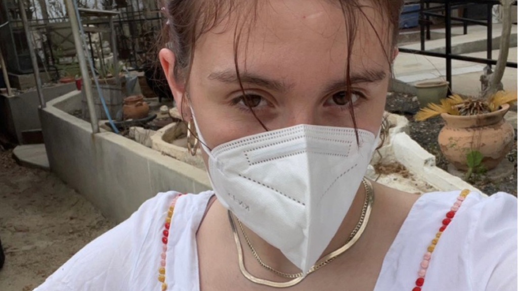 A photo of Erin Elizalde: she is facing the camera, hand on her hip, a KN95 mask covering the bottom half of her face.