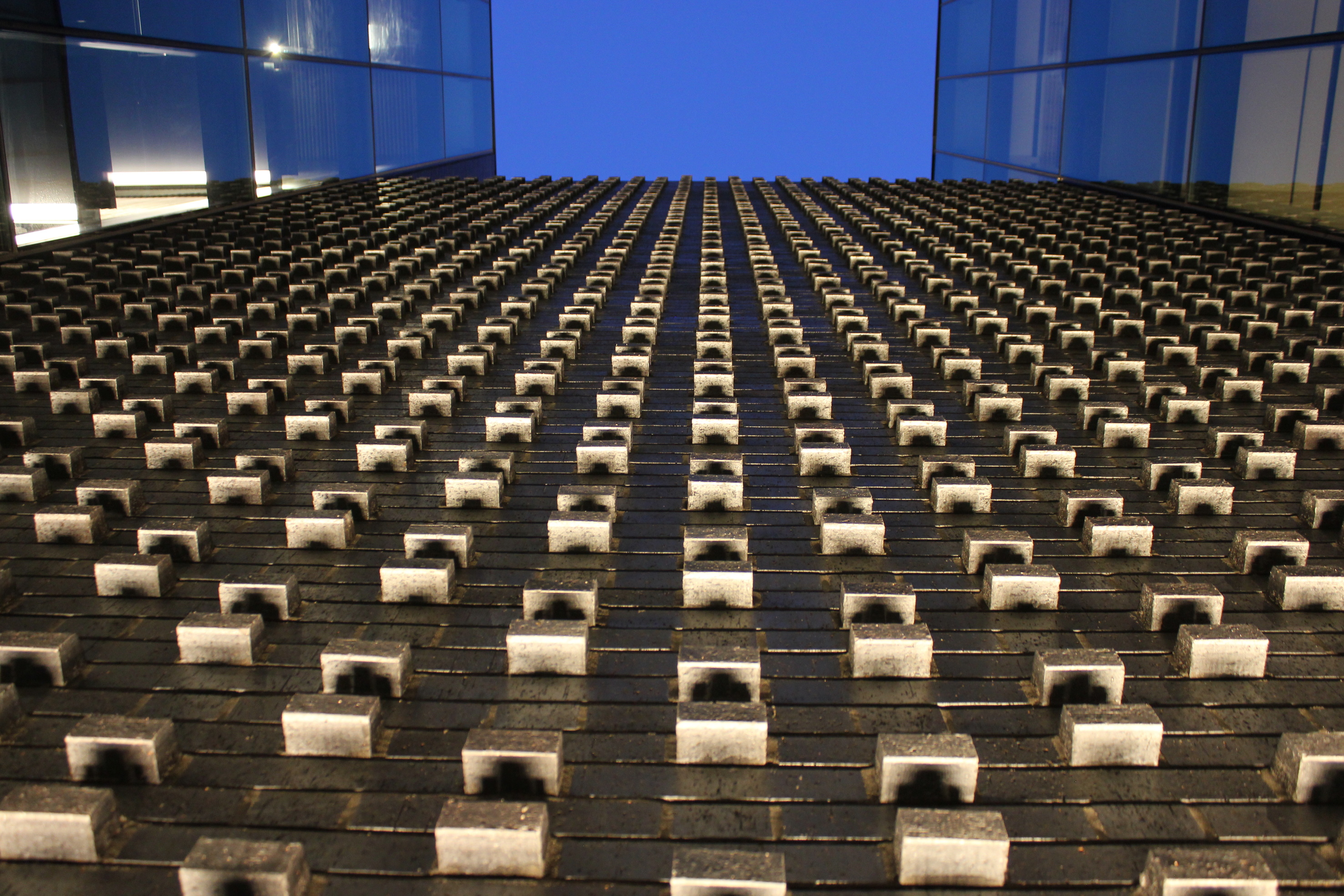 Looking up the lightwell past a brick wall lit from below toward a square of dark blue night ky.