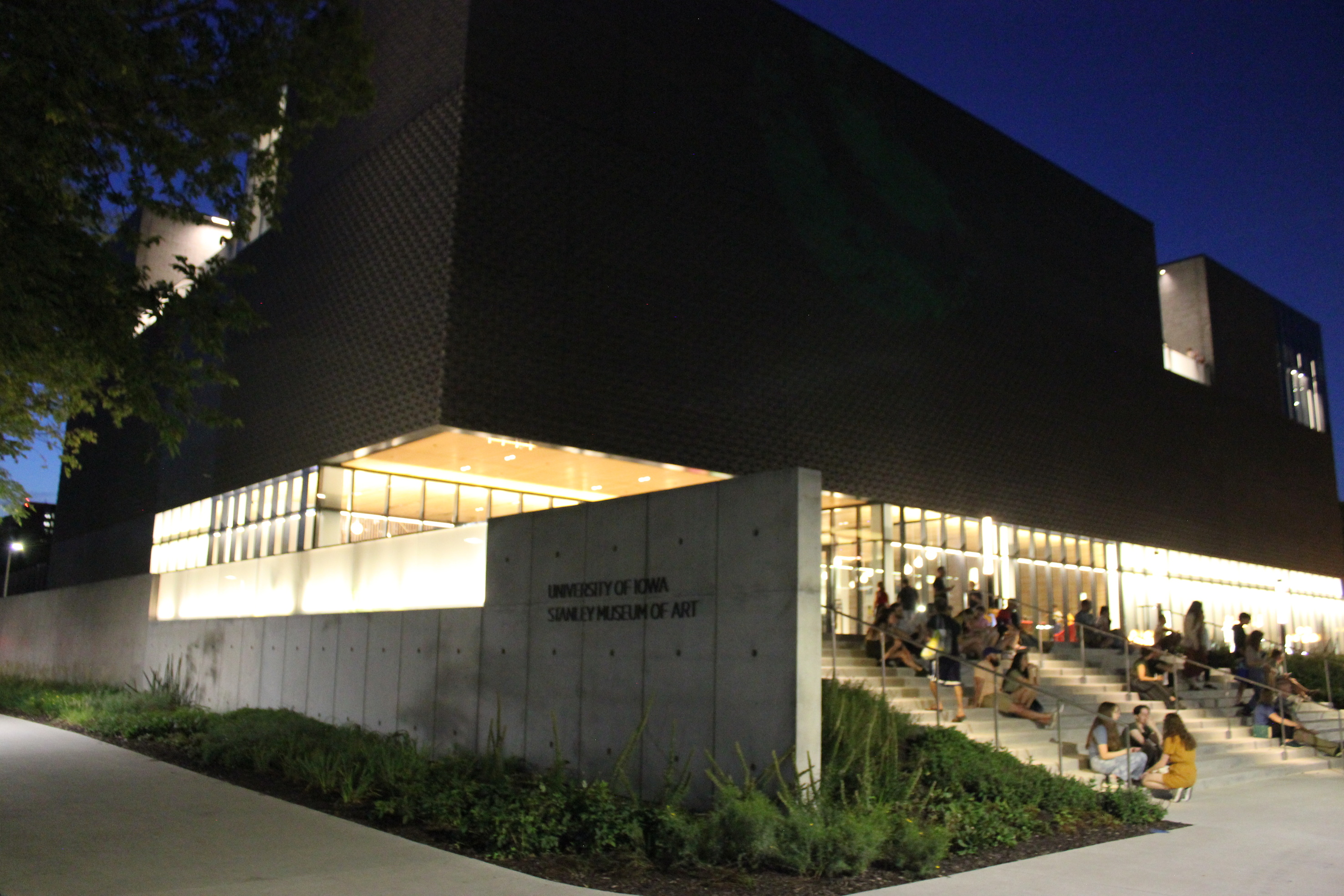 Front entrance of museum at night with the light from the lobby pouring outside