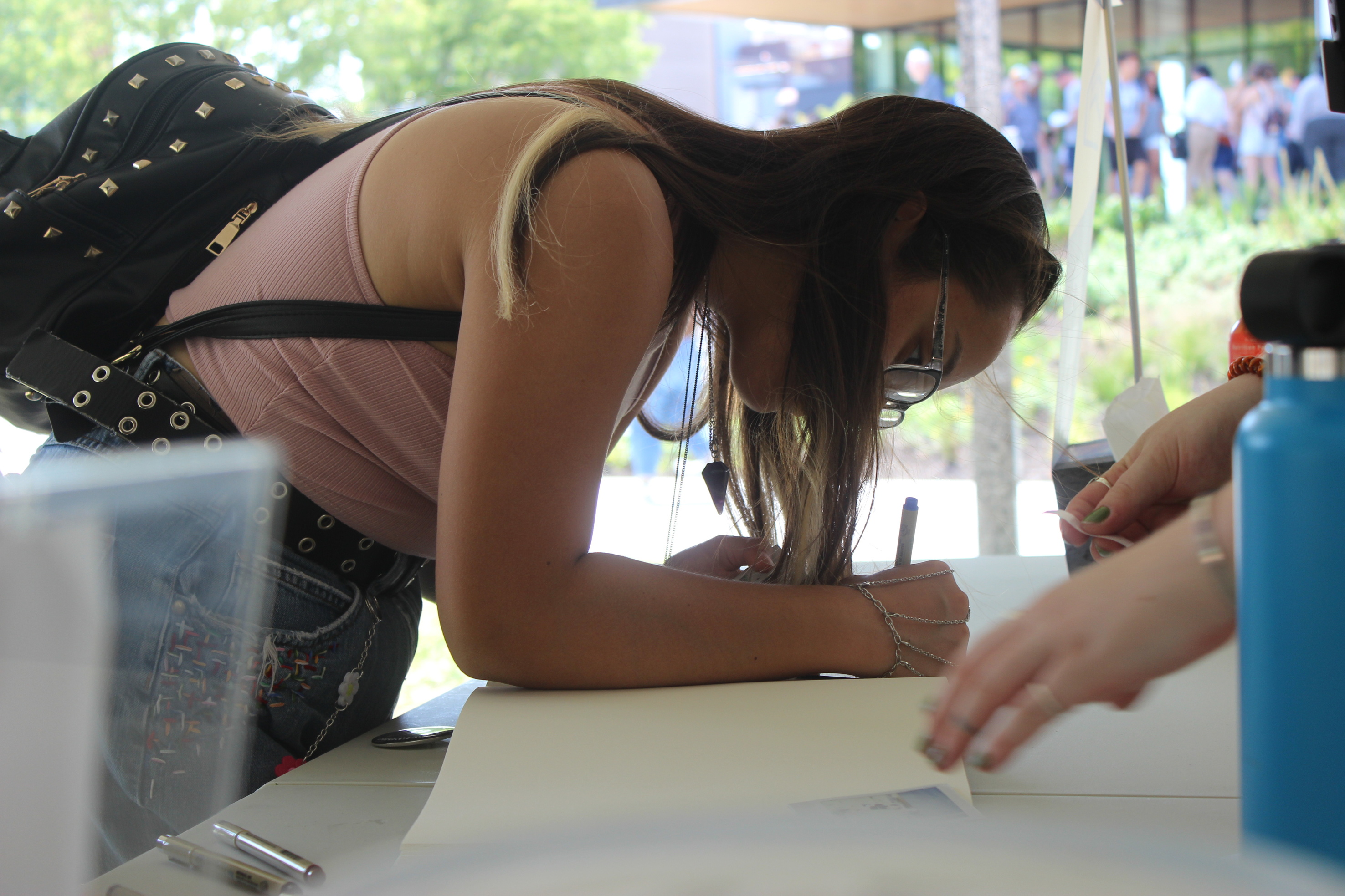 A woman leans over a table to sign a guest book