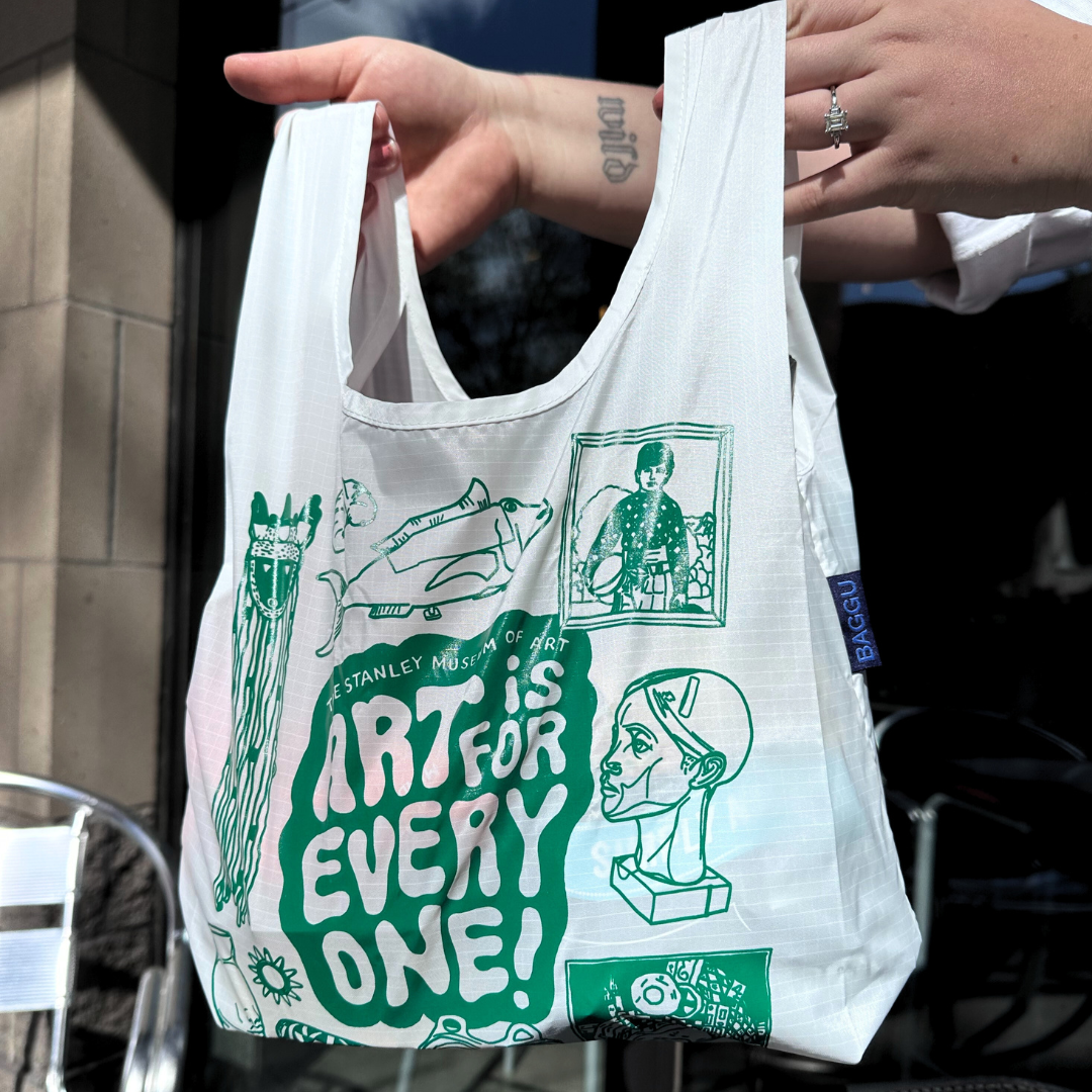 A photo featuring the Stanley Student Challenge Baggu bag prize. A white bag with green design on it, featuring the slogan "art is for everyone" and drawings of various works of art from the Stanley Museum of Art. 
