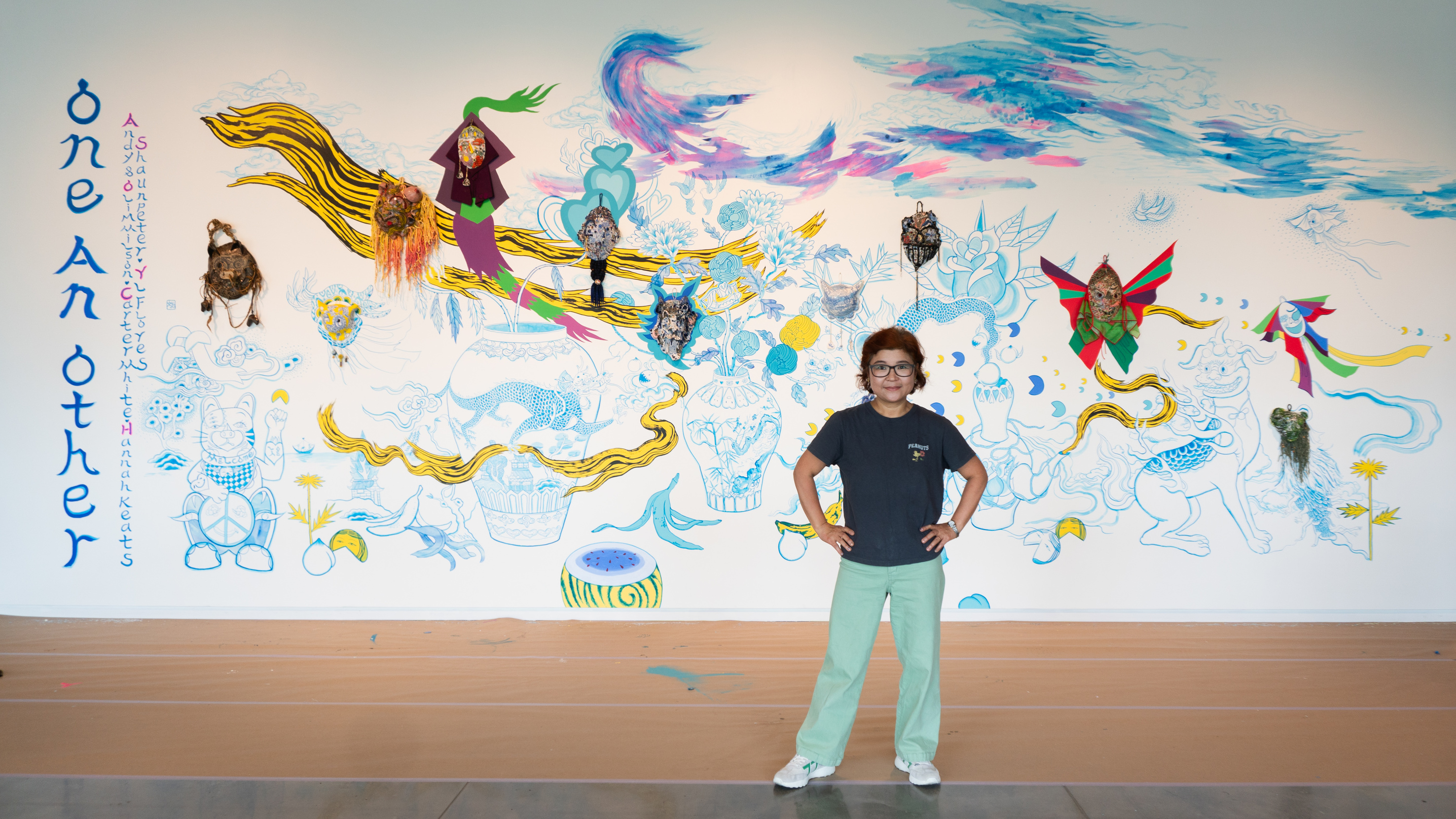 A person standing in front of a wide wall filled with drawings and painting