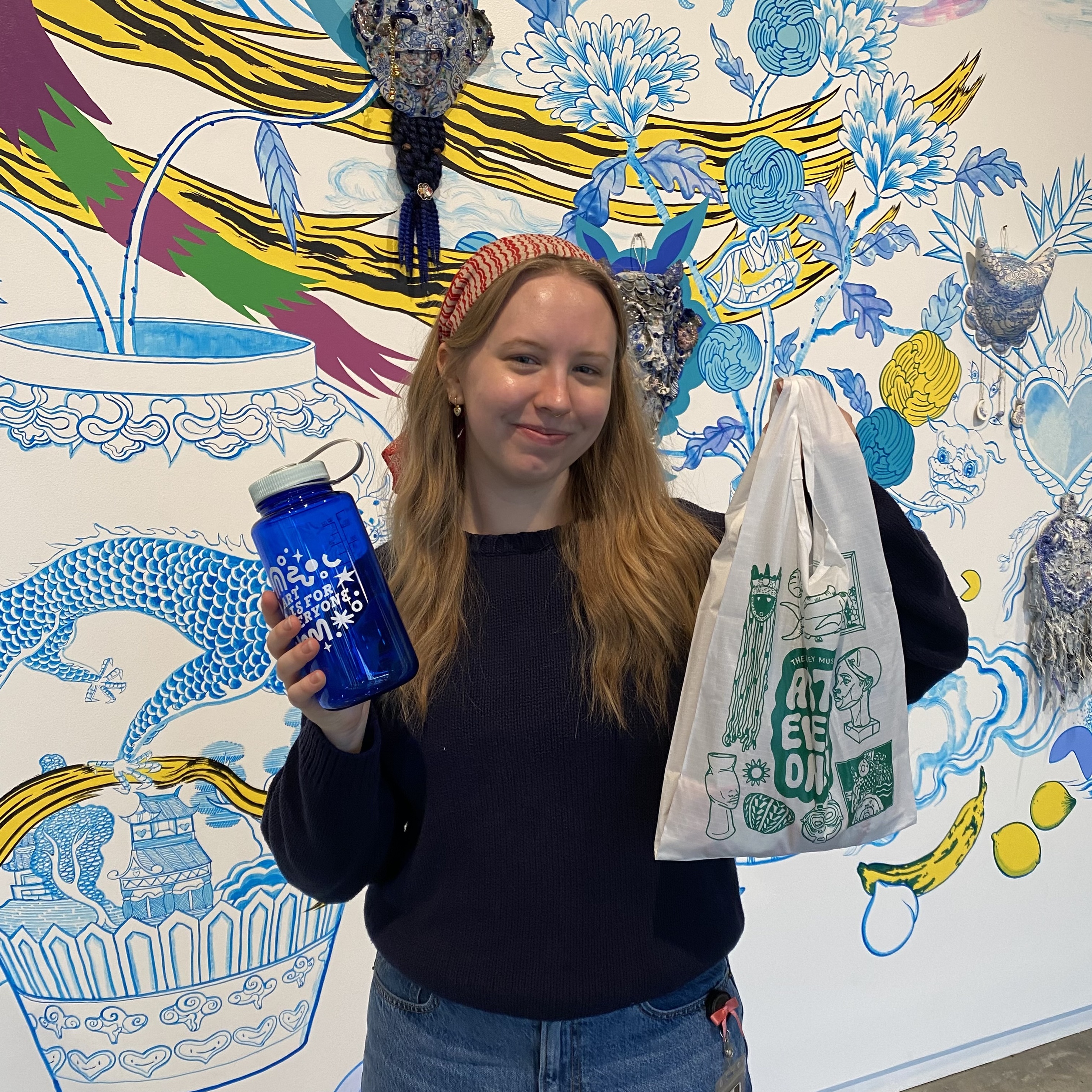 Gallery Host Josie holds up the two Stanley Student Challenge prizes--a custom Baggu and water bottle.