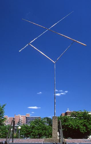A tall skinny “Y” shaped piece of steel with two metal rods attached to each point that intersect with each other maxing the shape of an “X”.