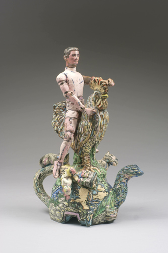 Sculpture of a person riding a large rooster, perched atop a teapot-shaped hill, with other animals surrounding.