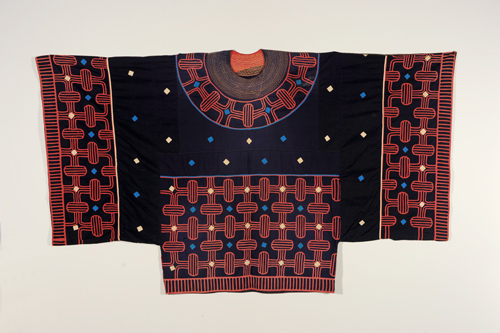 Garment with wide square sleeves. It has a navy base with detailed red patterns on the sleeves, around the neck, and on front bottom. Small yellow and blue diamonds are scattered throughout.