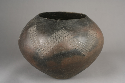 Pot with narrow base, wide middle, and narrower top, with a “W” shape made of textural dots.