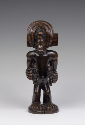 Wooden figure of a Chokwe chief wearing an elaborate crown and holding small figures of male and female ancestors.