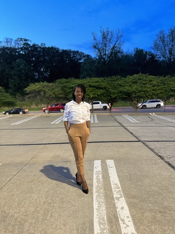 A photo of Nyari Chisaka - she poses, smiling, in a parking lot.