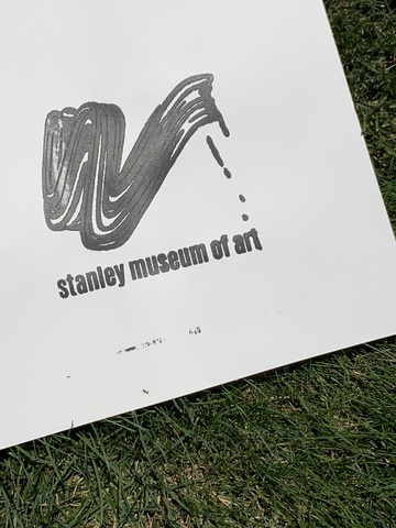 An image of a test print on paper, with black ink, laying on the grass outdoors.