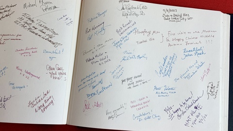 A photograph of the Stanley Museum of art guestbook. Signatures and written messages in different colors fill the large white pages.