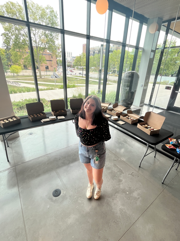 A photo of Alexis, the Stanley's Campus Engagement Coordinator and the student in charge of the HBD event, posing in front of the tables with the cupcakes on them.