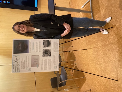 Amelia Goldsby poses next to her poster presentation on provenance research and her experience at the Stanley.