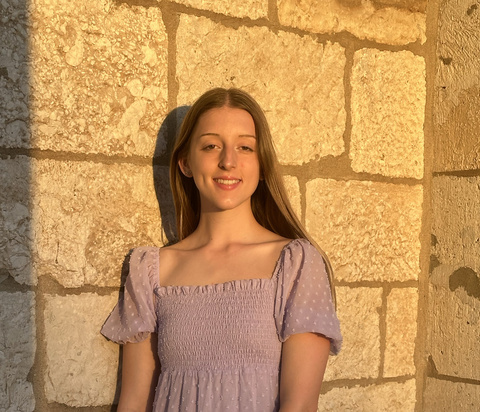 Faith McPhillips, Gallery Host, poses in front of the Old Capitol building.