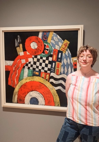 Lauren Smith poses in front of Marsden Hartley's painting, "E," in the Stanley Museum of Art's galleries.