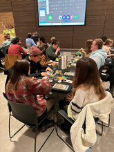 shown is a full table of students playing bingo. The table is covered with a black table cloth and has bingo cards and Jolly Ranchers on it 