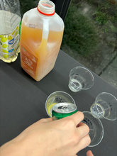 close up image of a hand pouring a canned ginger ale into a clear plastic cup 