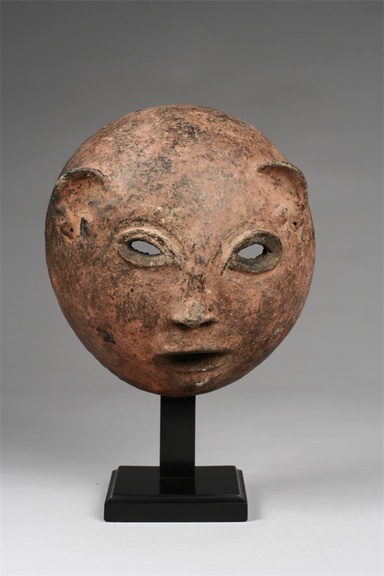 A clay mask mounted on a small metal stand depicting facial features