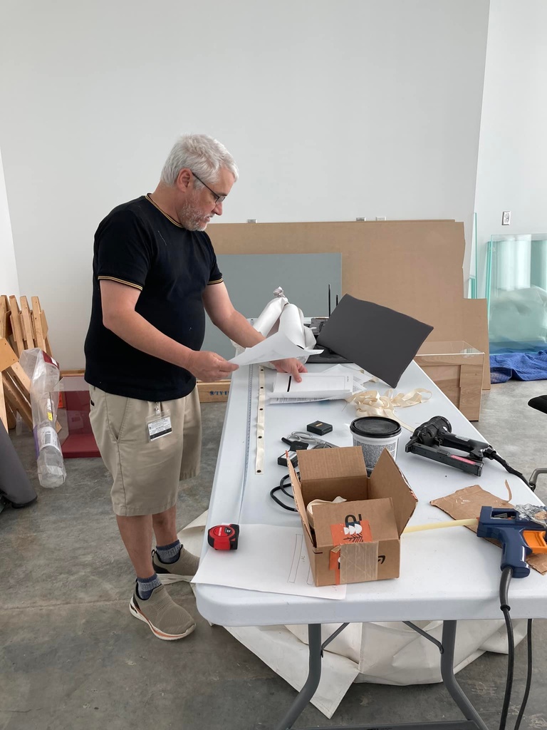 Man with short white hair and glasses sorts tools on a table