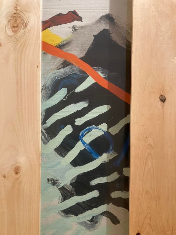 A small section of an abstract painting seen between wooden slats of packing crate. 