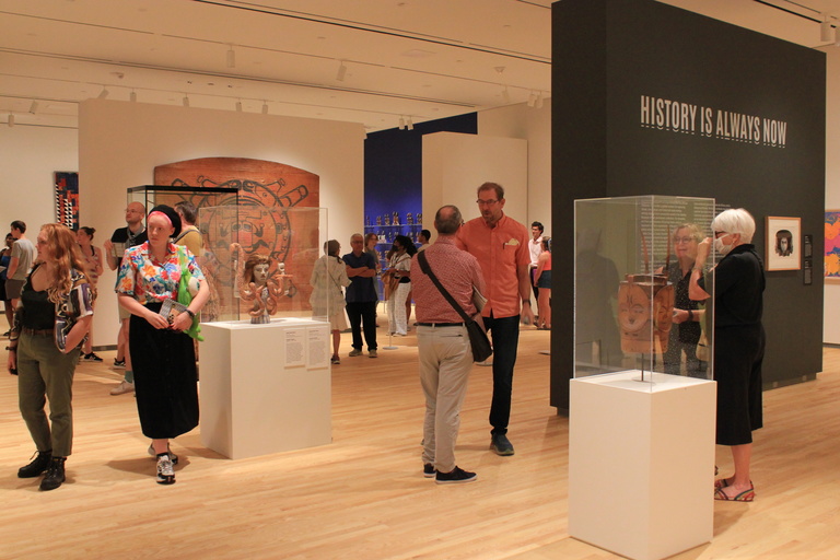 Visitors in a museum gallery look at framed artwork and sculptures