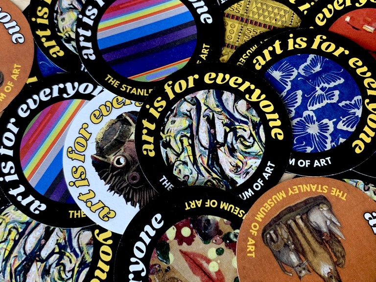 An up-close image of a pile of pinback buttons. Each button reads "art is for everyone" and features an image of a work of art from the Stanley's collection.