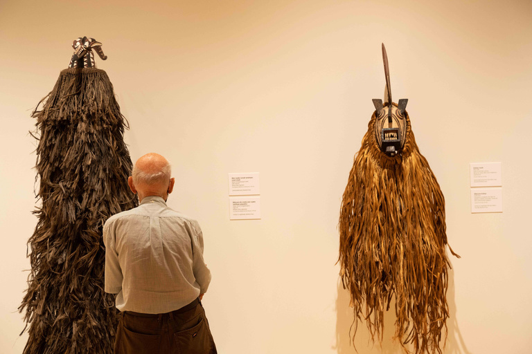 A guest looking at two large, tall, fiber-based masks.