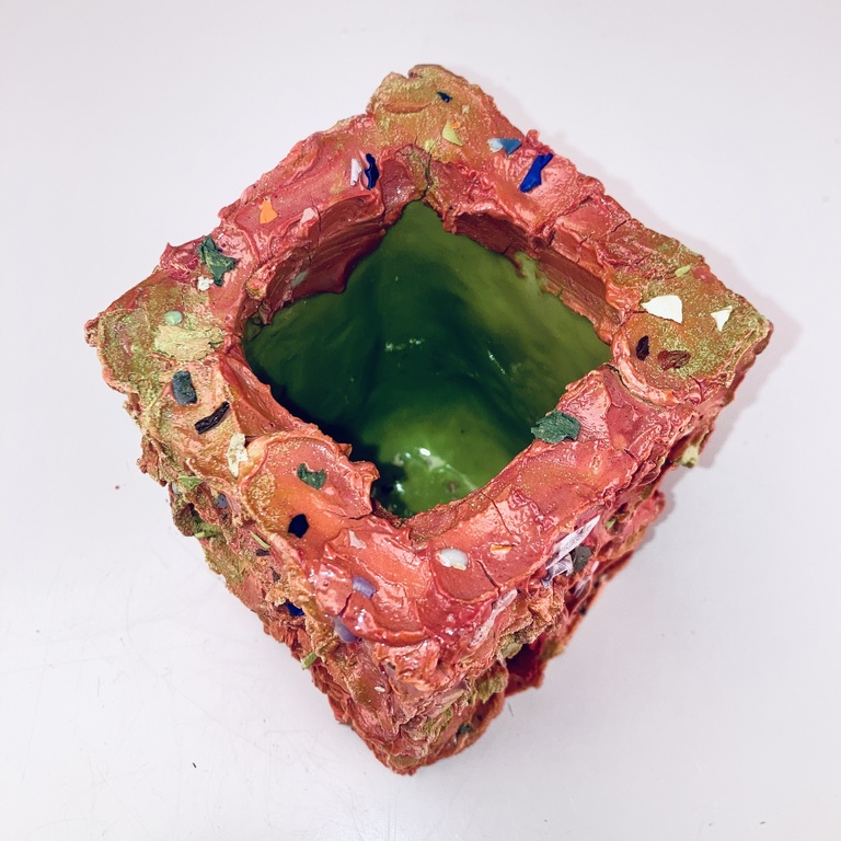 Alyson's work: a pink ceramic cube shaped vessel, with a green interior.