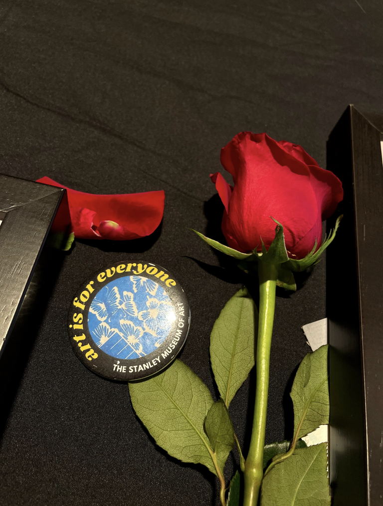 A photo of the free favors available at the SCC event: a red rose for the participating artists and a pinback button that says "art is for everyone."