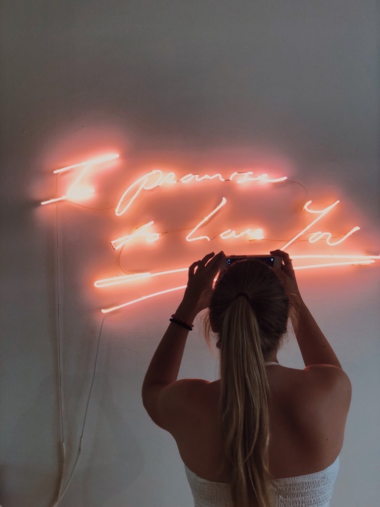 Aubrie's art: a photograph of a woman posing in front of a neon sign. 