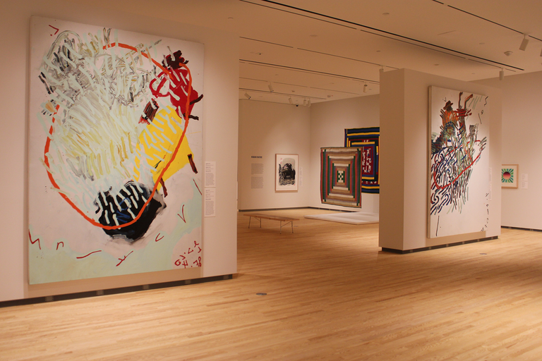 An installation shot of the galleries at the Stanley Museum of Art. In the foreground, two large works by Oliver Lee Jackson can be seen; behind them, a glimpse at Gee's Bend quilts.