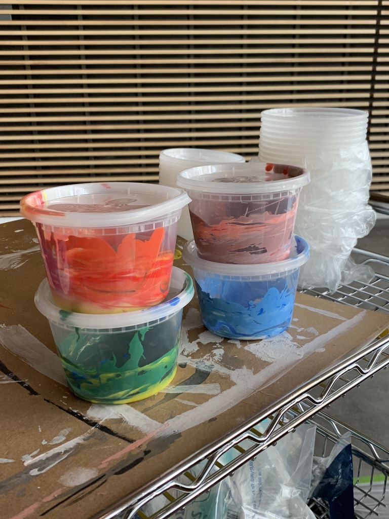 A photo of little plastic containers of ink; there are four of them, two stacks of two. An orangey ink is stacked atop a green ink, and a light pink ink is stacked atop a sky blue.