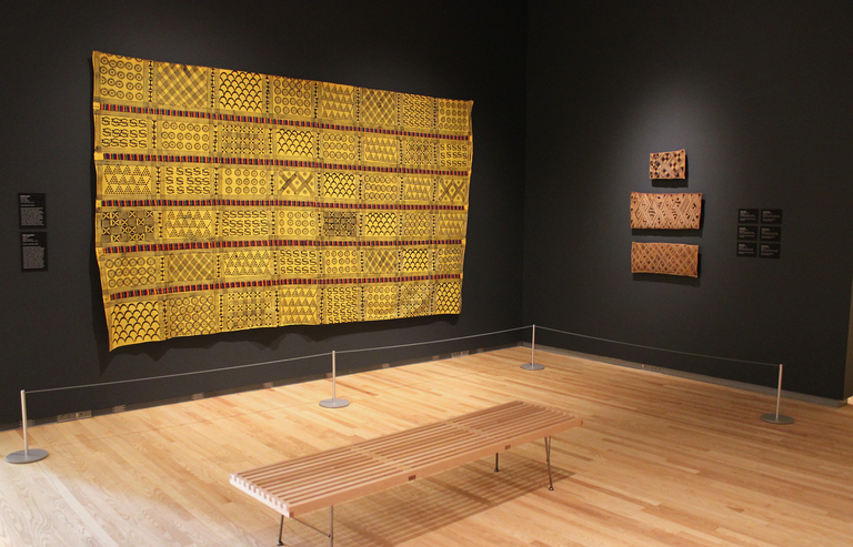 An installation shot of "Centering on Cloth," featuring a large yellow adinkra cloth.