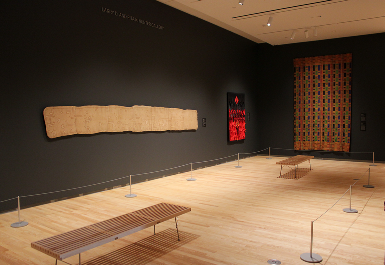 An installation shot of "Centering on Cloth:" featuring three distinct textile works.
