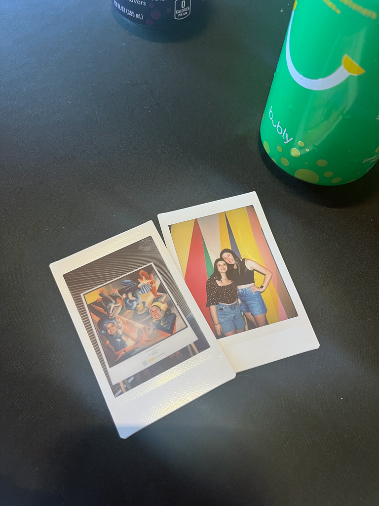 A photo of two Polaroid pictures, taken at HBD SMA on a black tablecloth. 