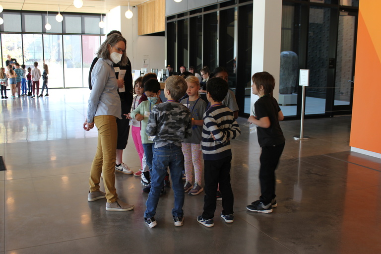 a group of children with an adult in a large, open lobby