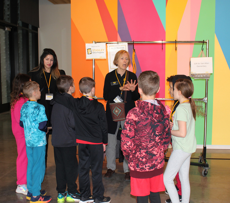 Elementary school student group standing with a docent and coat rack