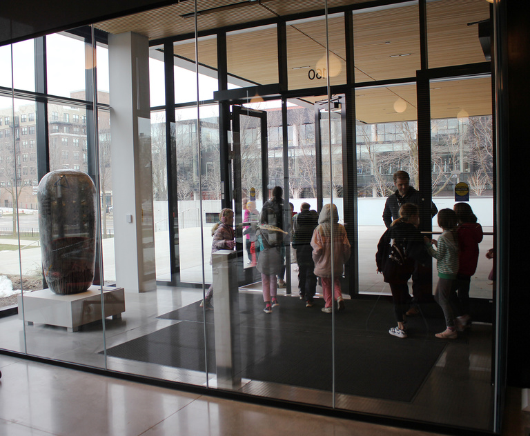 School children exit the museum through the glass vestibule.