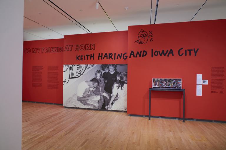 Gallery space with a red baffle wall that reads, "To My Friends at Horn: Keith Haring and Iowa City"