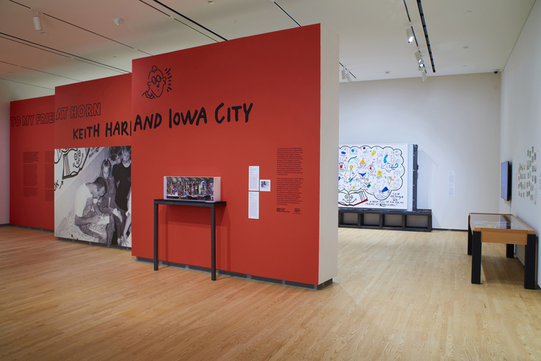 Gallery space with a red baffle wall that reads, "To My Friends at Horn: Keith Haring and Iowa City"