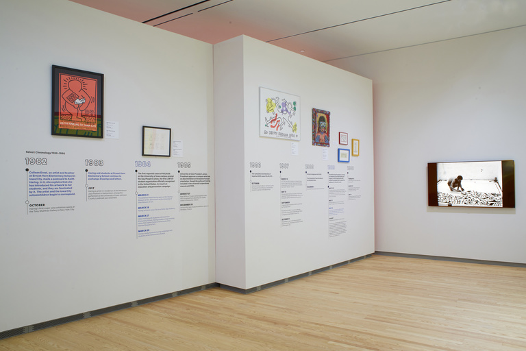 Gallery wall displaying a variety of framed artworks and text in the form of a timeline
