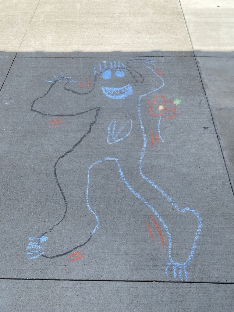 A photo of the ground with sidewalk chalk drawings, featuring outlines drawn of people that resemble Keith Haring-style figures. 