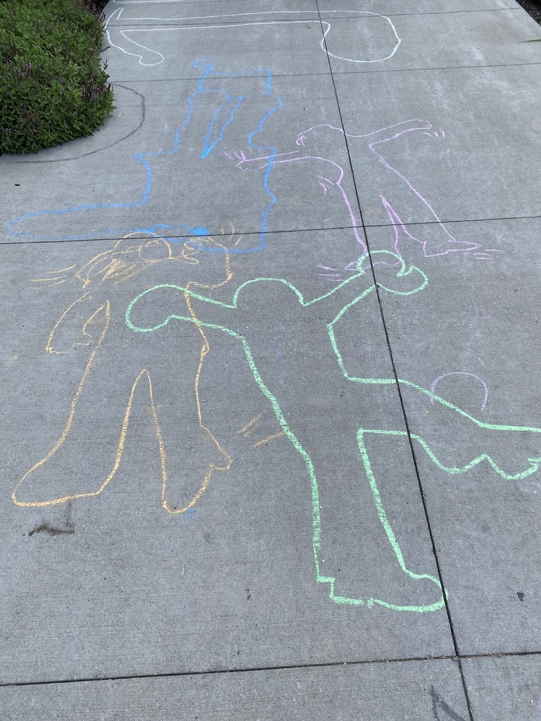 A photo of the ground with sidewalk chalk drawings, featuring outlines drawn of people that resemble Keith Haring-style figures. 