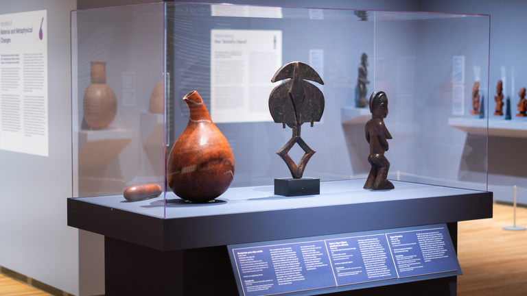 Image of a display case with African art on display on a purple walls and 