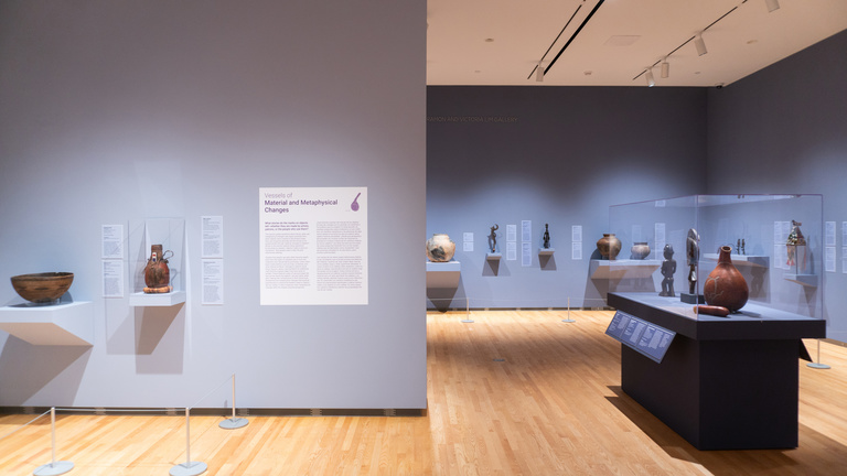 Image of a gallery with purple walls and African art on display