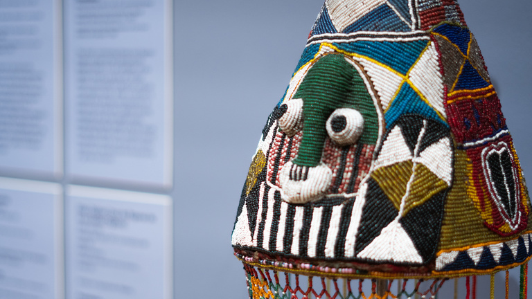 A ceremonial head piece made of colorful glass beads, cotton, fiber, wood, and thread