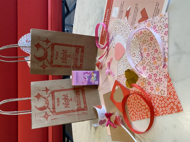 A photo of two valentine's craft bags and their contents: candies, blank valentines, ribbons, stickers, and more.