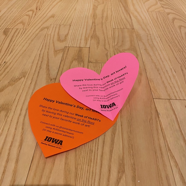 Two paper hearts on the wood floor.